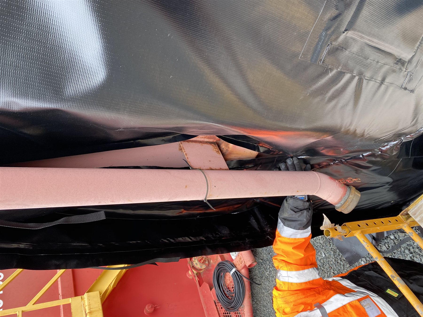 Installer securing a Powerblanket frac tank heating blanket in place on an active site