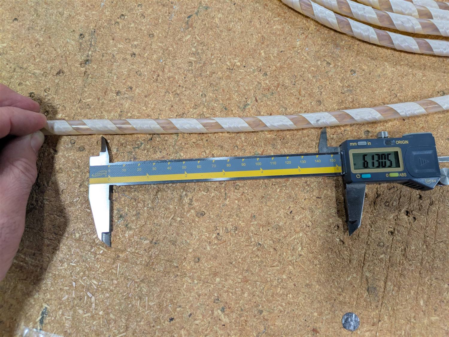 Digital caliper measuring the outside diameter of a spiral-taped tube during quality control